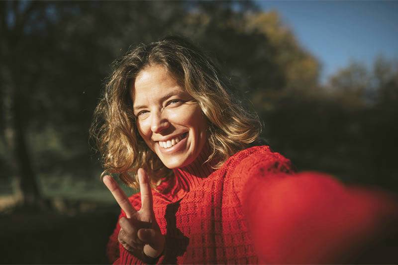 Adult woman smiling and holding up two fingers.